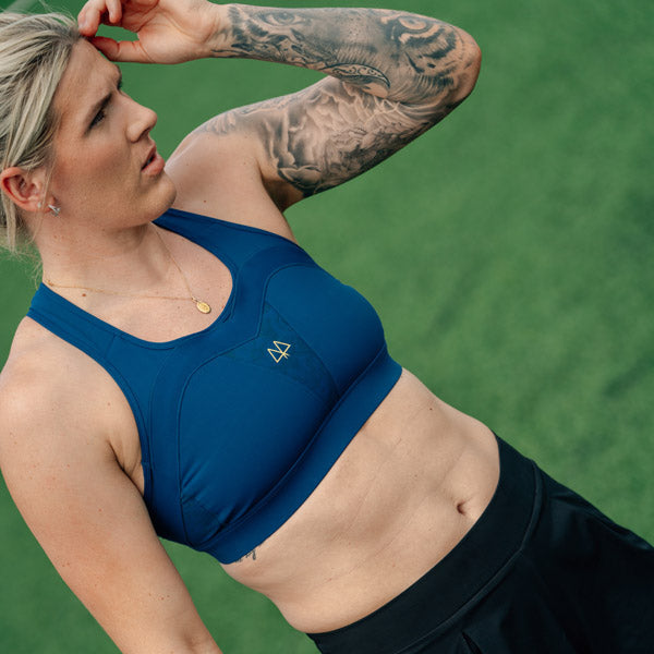 Woman in blue sports bra and black shorts on a green field