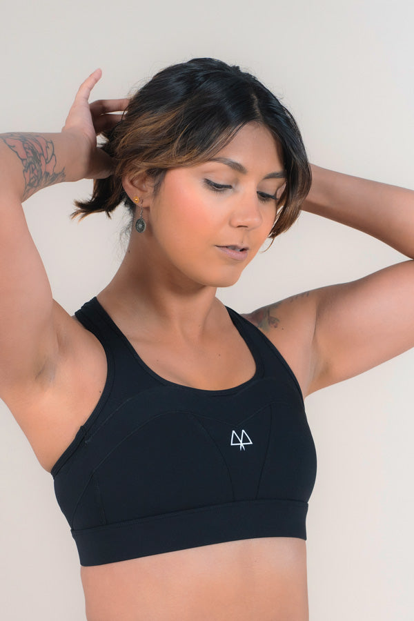 Woman standing with the MAAREE Empower Sports Bra in Back, adjusting her hair.