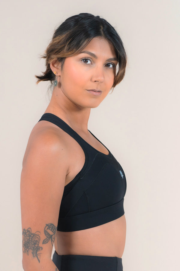 Woman standing with a side profile wearing a Black sports bra