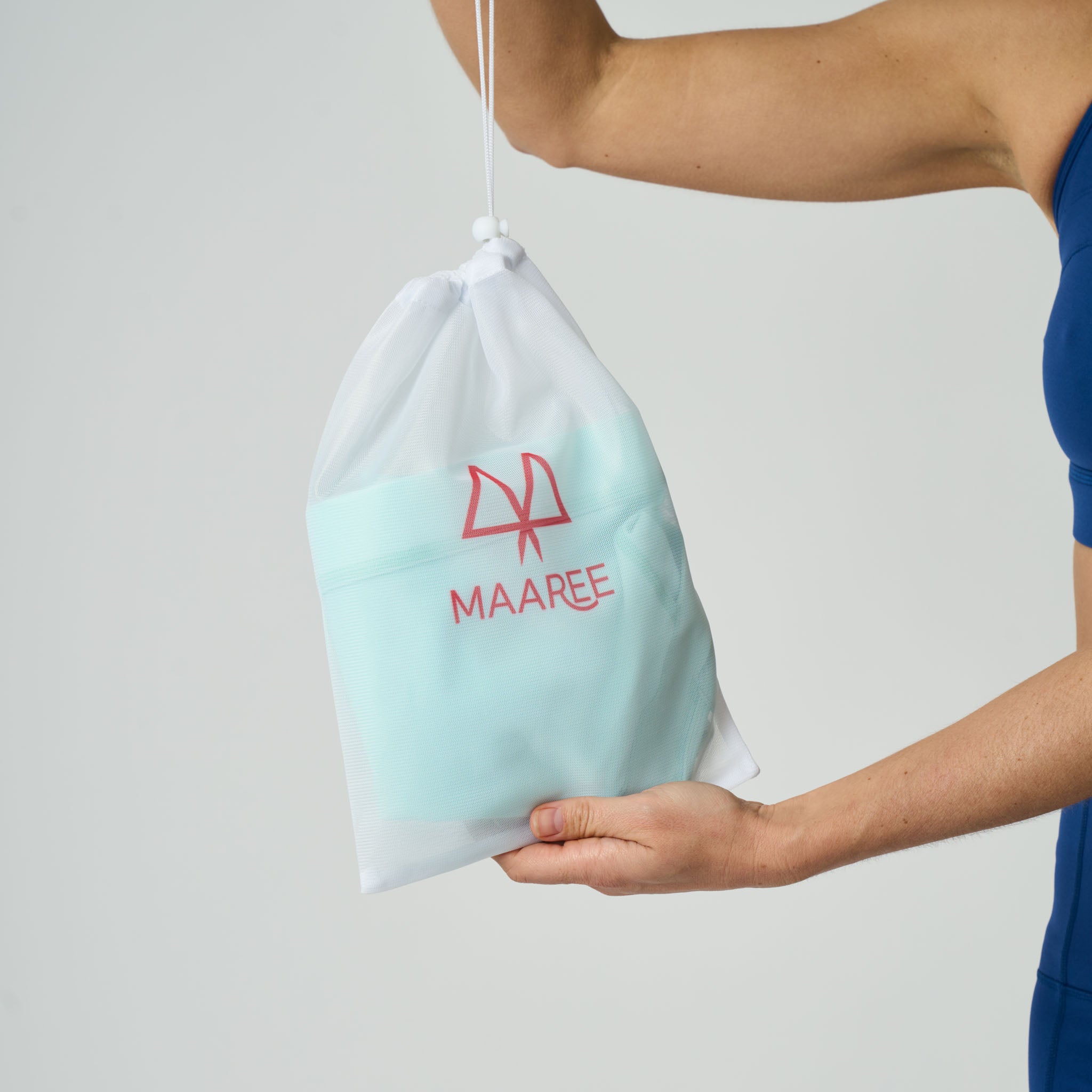 Person holding a light blue drawstring bra wash bag with 'MAAREE' branding against a plain background