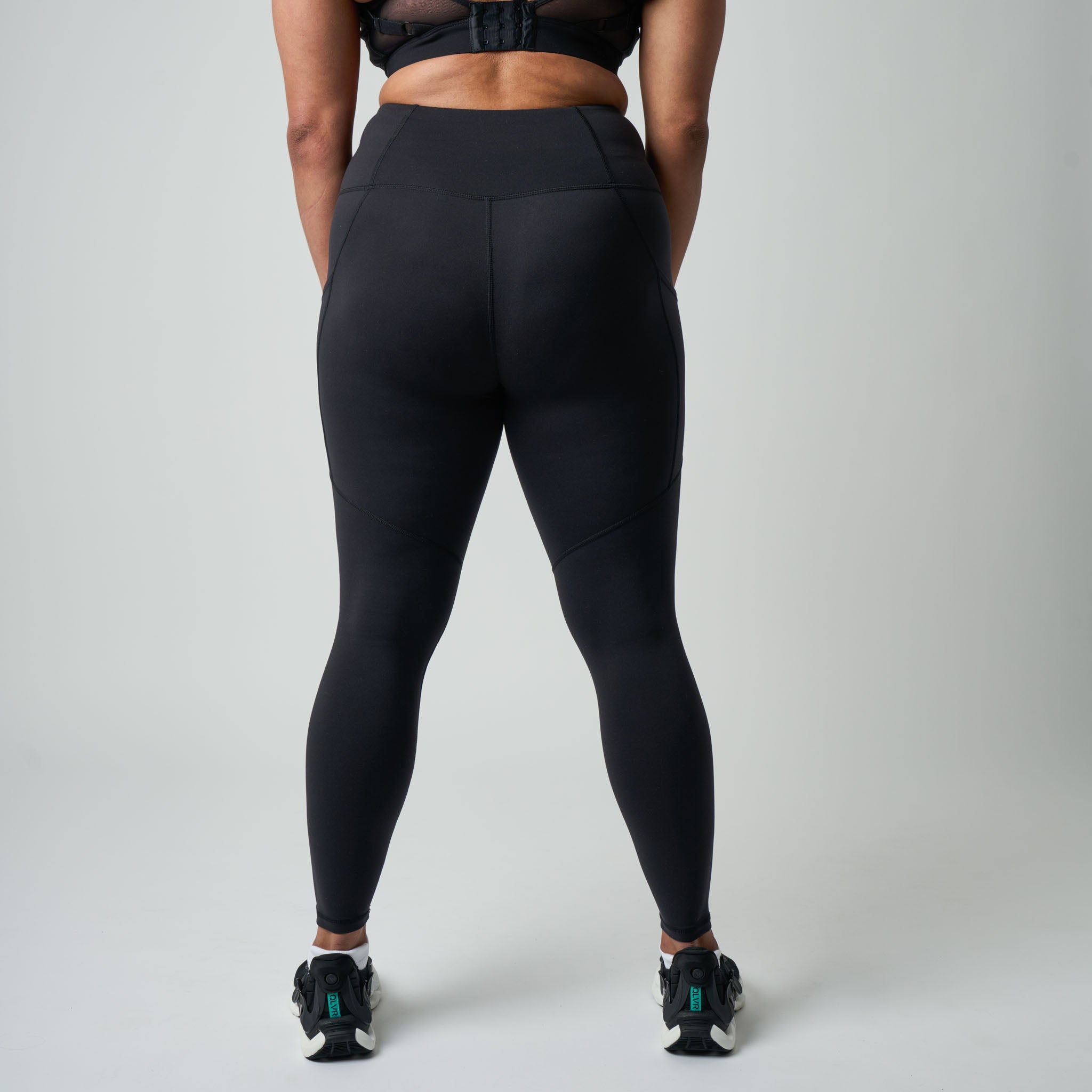 Person wearing black leggings on a plain background