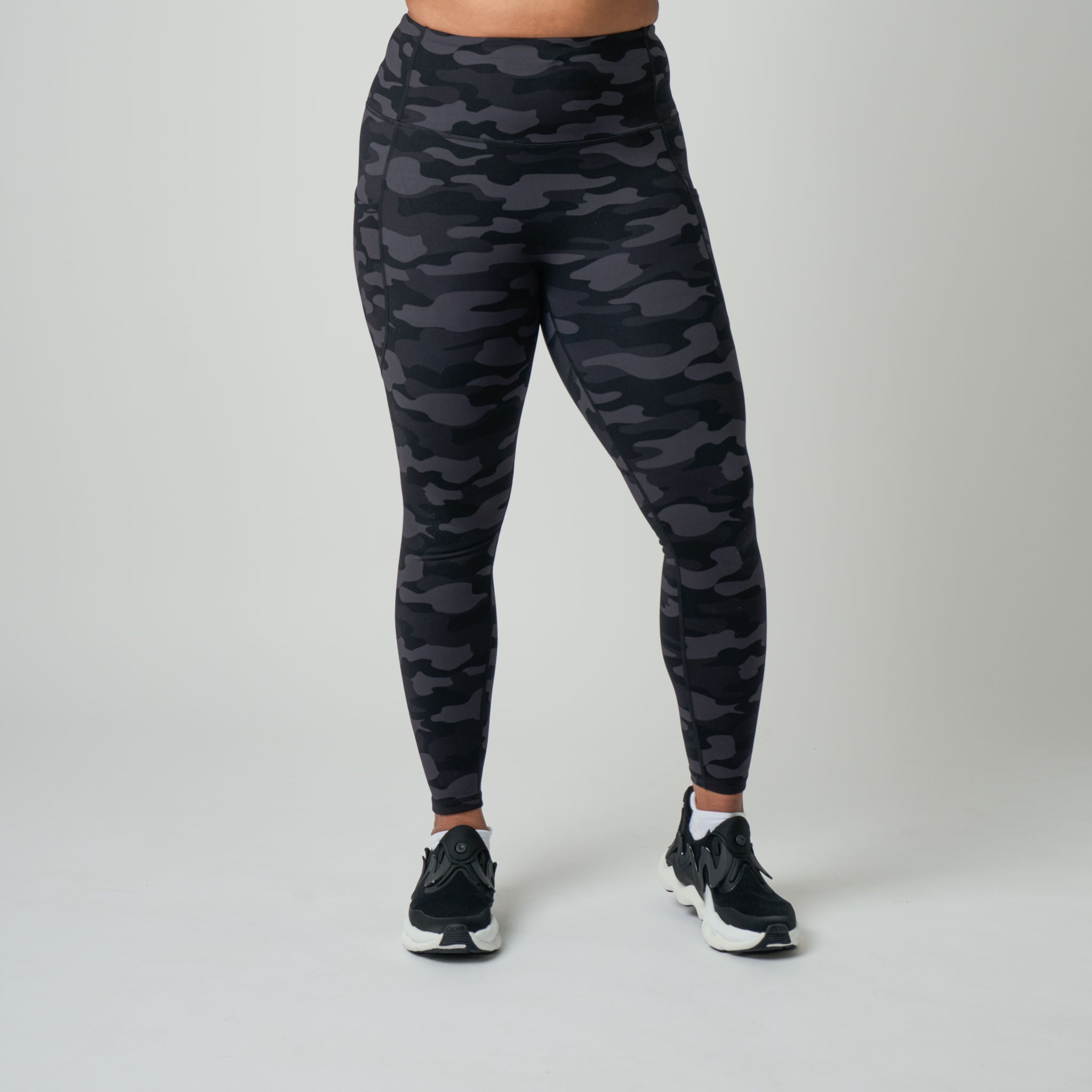 Person wearing black camouflage leggings on a gray background