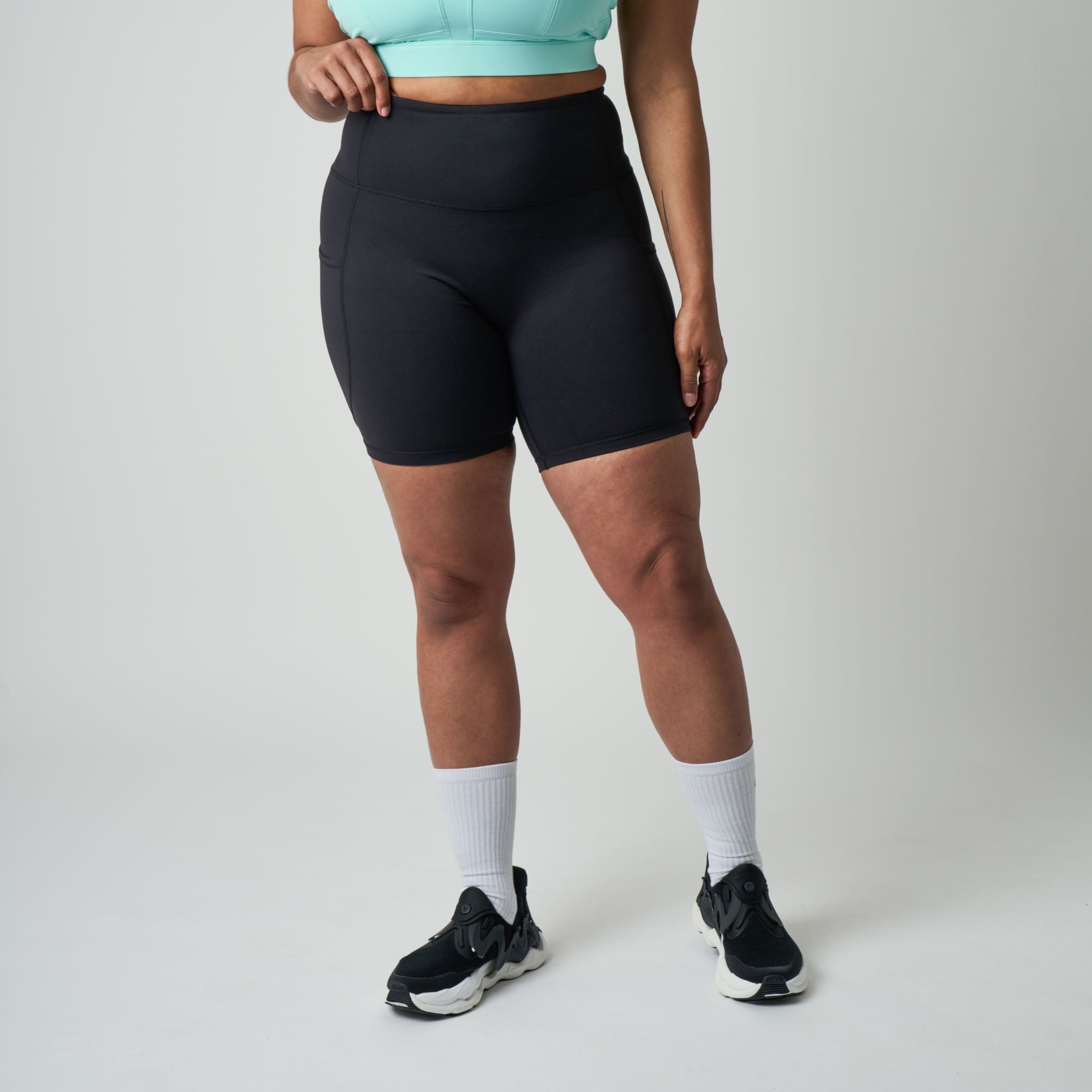 Person wearing black athletic shorts on a plain background