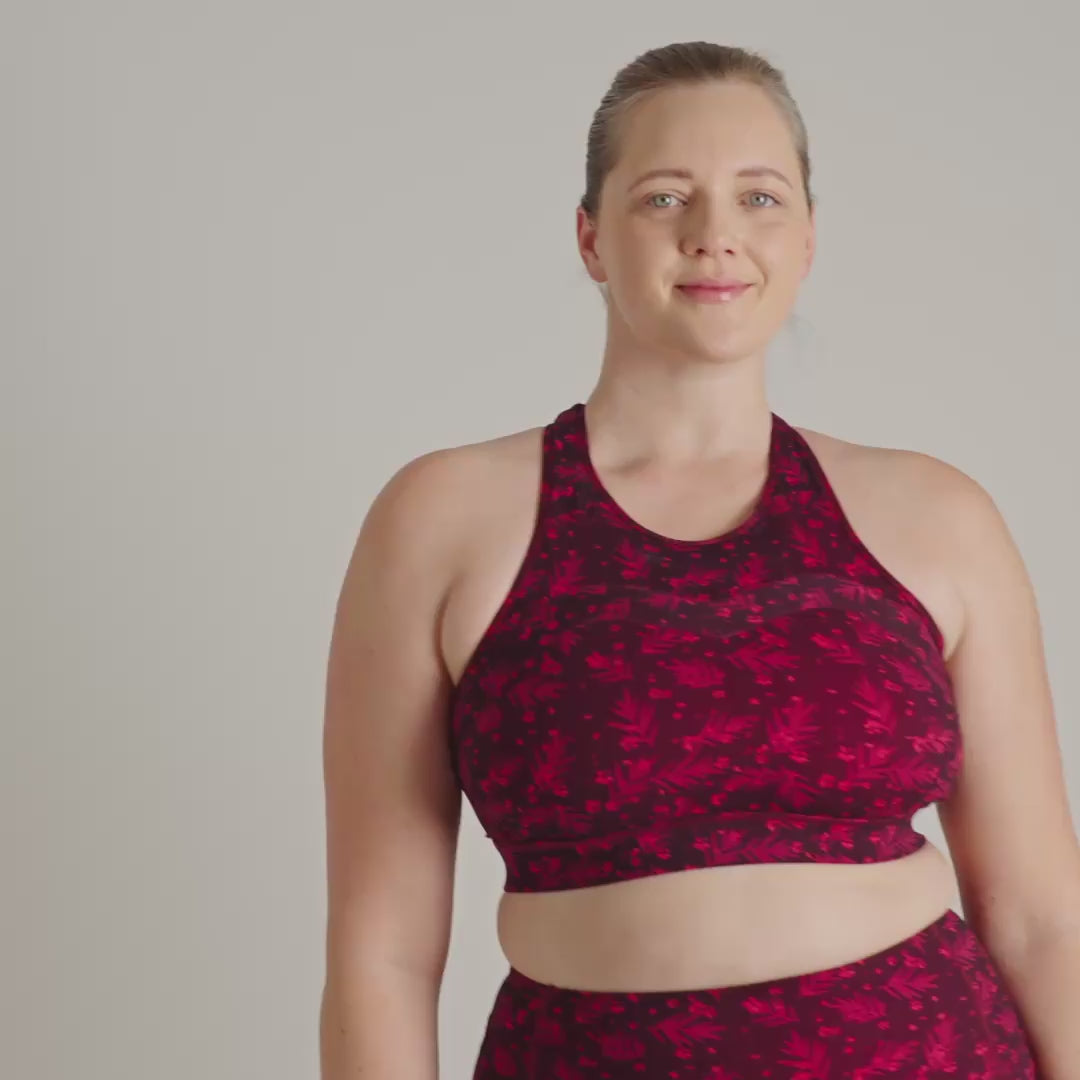 Person wearing a red and black patterned sports bra and leggings on a plain background